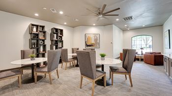 A room with a white table and grey chairs.